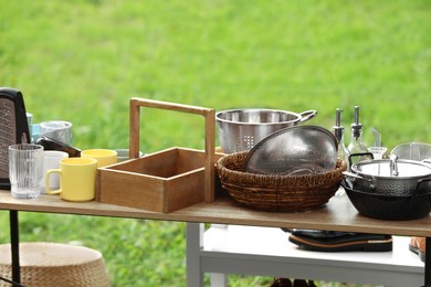 Photo of Many different items on wooden table outdoors. Garage sale