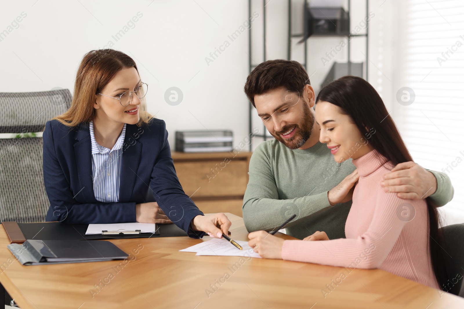 Photo of Happy couple signing document in lawyer's office