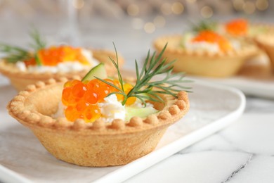 Delicious canapes with red caviar on white marble table, closeup