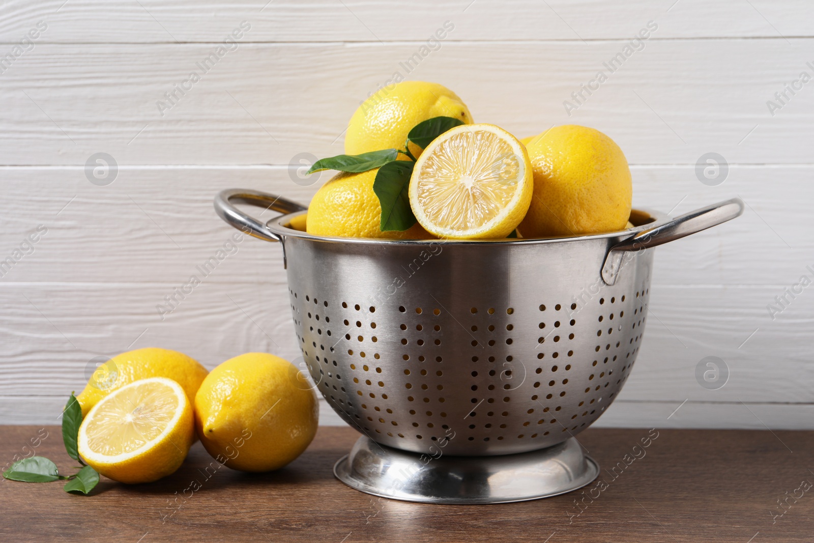 Photo of Fresh lemons and green leaves on wooden table