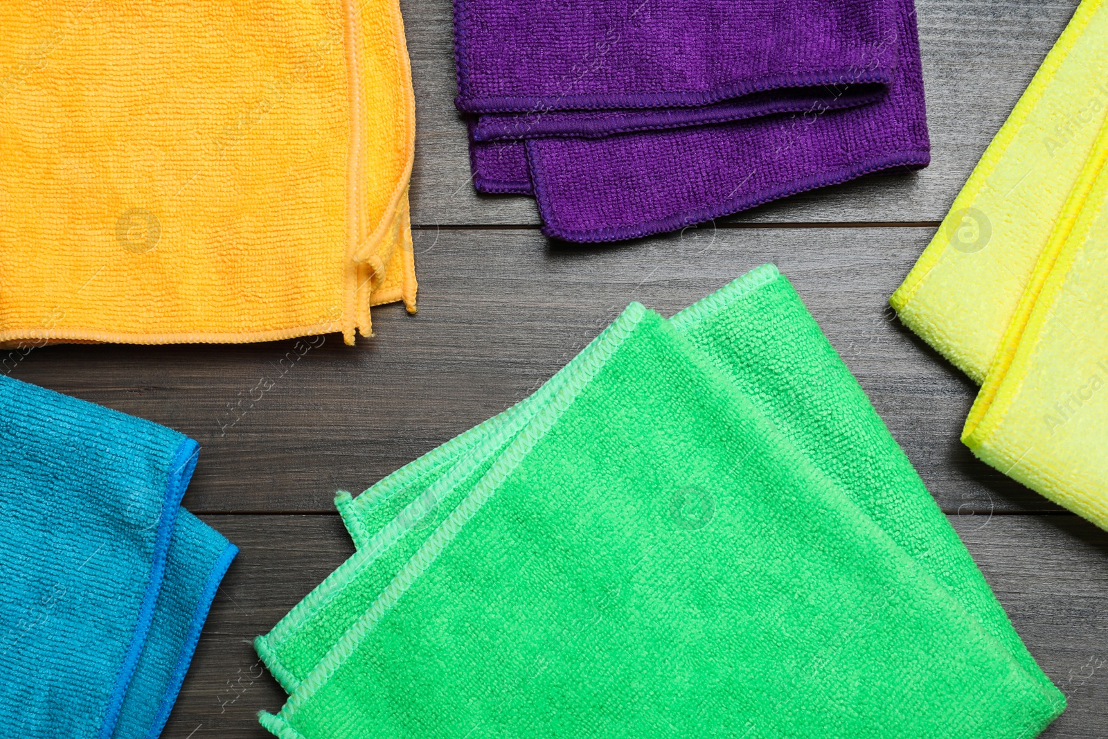 Photo of Many colorful microfiber cloths on wooden table, flat lay