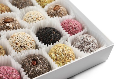 Photo of Different delicious vegan candy balls in box on white background, closeup
