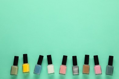 Bright nail polishes in bottles on turquoise background, flat lay. Space for text