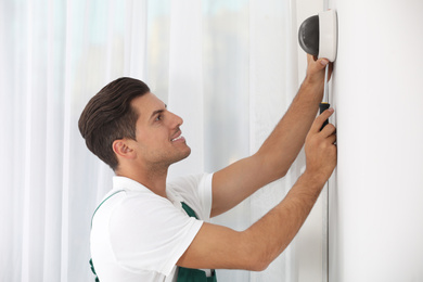 Photo of Technician installing CCTV camera on wall indoors