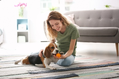 Photo of Young woman playing with her dog at home