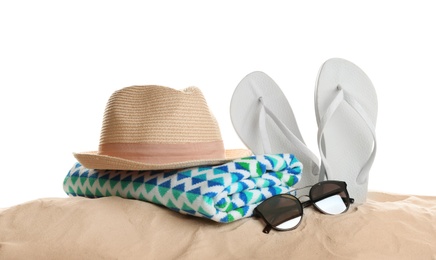 Different beach accessories on sand against white background