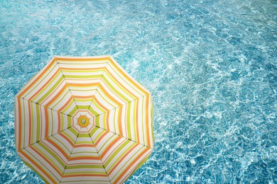 Image of Open beach umbrella and swimming pool. Summer vacation