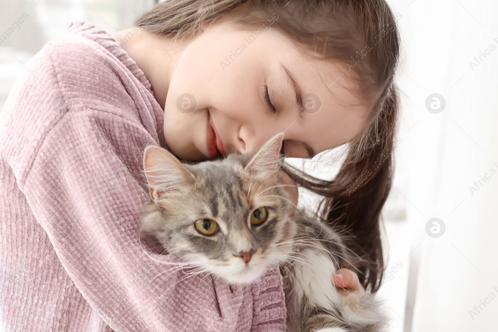 Photo of Cute little girl with cat near window at home