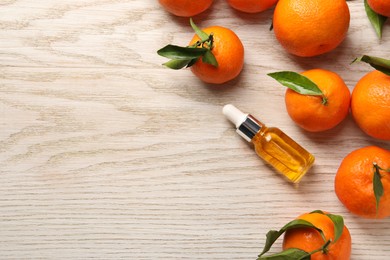 Bottle of tangerine essential oil and fresh fruits on white wooden table, flat lay. Space for text