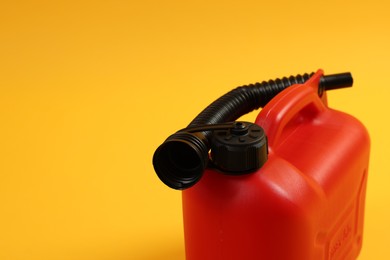 Red plastic canister with tube on orange background, closeup. Space for text