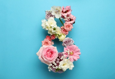 Number 8 made of beautiful flowers on light blue background, flat lay. International Women's day