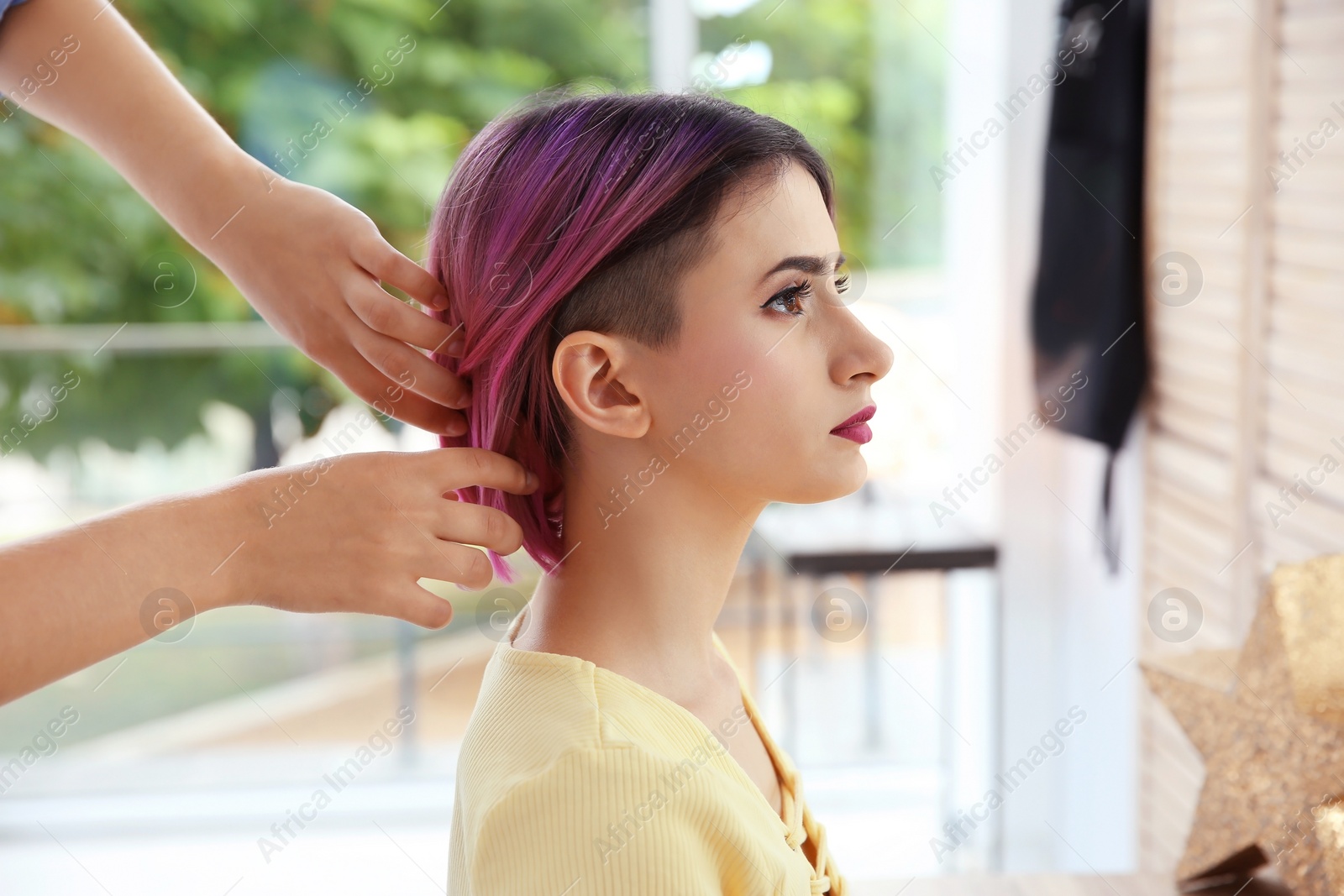 Photo of Professional hairdresser working with young woman in beauty salon. Trendy hair color