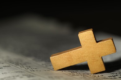 Photo of Wooden Christian cross on Bible, closeup. Space for text