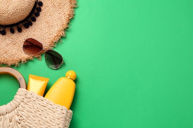Photo of Flat lay composition with stylish straw hat and beach accessories on green background, space for text