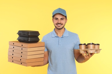 Young courier with different orders on color background. Food delivery service