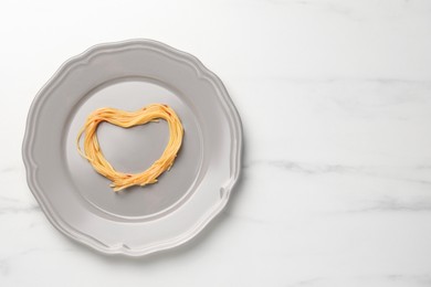 Photo of Heart made with spaghetti on white table, top view. Space for text