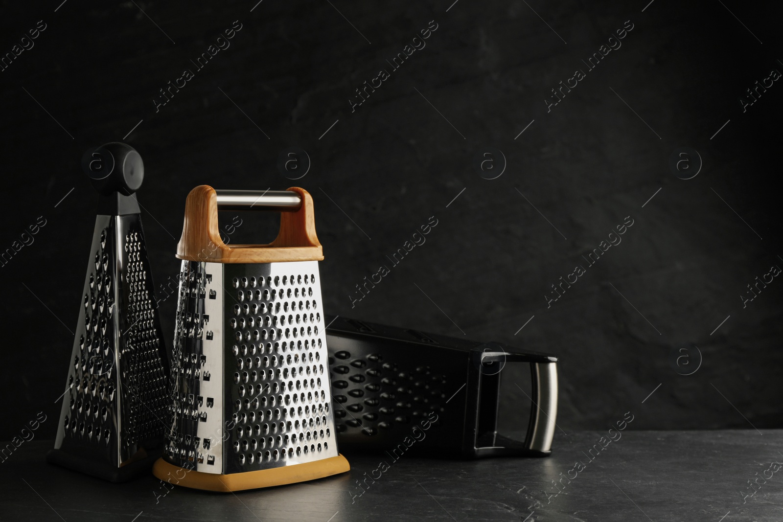 Photo of Different modern graters on black table. Space for text