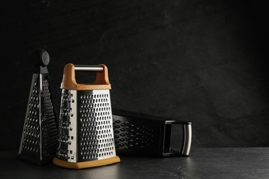 Photo of Different modern graters on black table. Space for text
