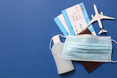 Photo of Flat lay composition with passport and protective mask on blue background, space for text. Travel during quarantine