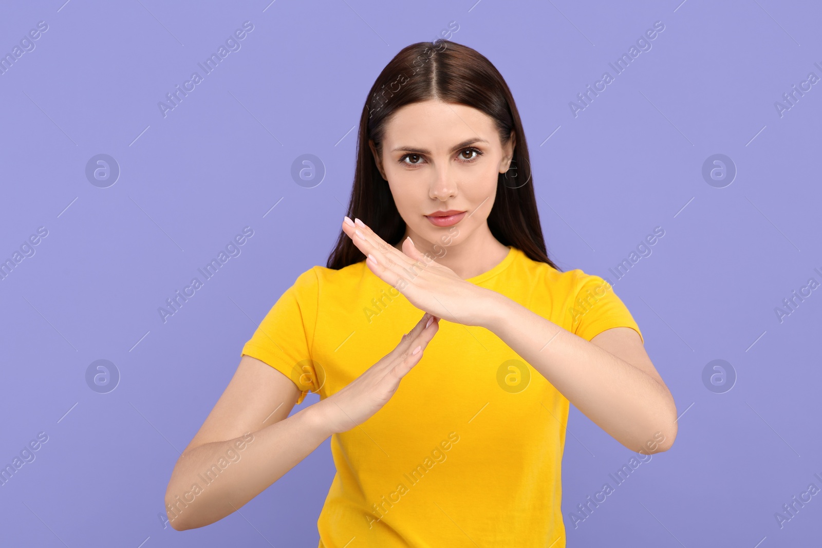 Photo of Woman showing time out gesture on violet background