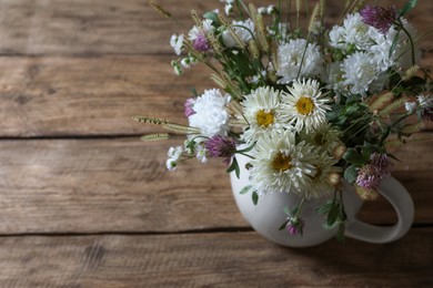 Beautiful wild flowers and spikelets on wooden table, closeup. Space for text