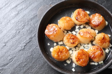 Photo of Delicious fried scallops on dark gray textured table, top view. Space for text