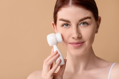 Photo of Washing face. Young woman with cleansing brush on beige background, space for text