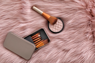 Photo of Flat lay composition with makeup brushes and powder on faux fur