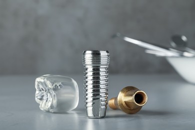 Parts of dental implant on grey table, closeup