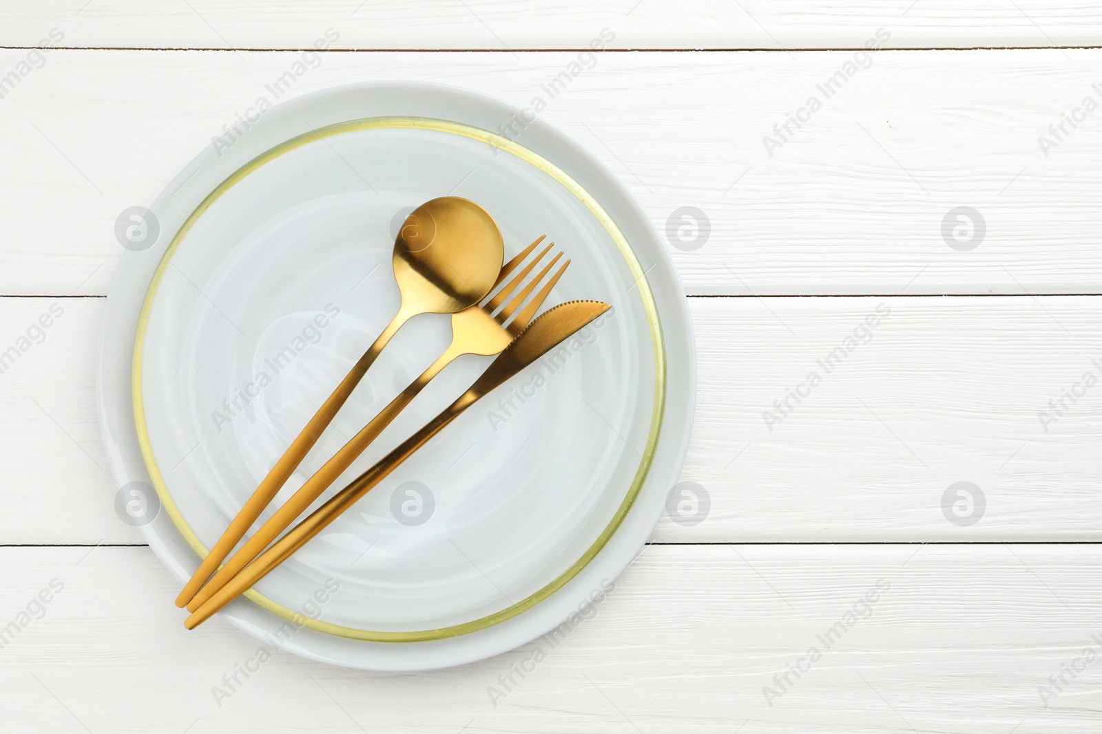 Photo of Stylish setting with cutlery and plate on white wooden table, top view. Space for text