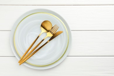 Photo of Stylish setting with cutlery and plate on white wooden table, top view. Space for text