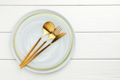 Stylish setting with cutlery and plate on white wooden table, top view. Space for text