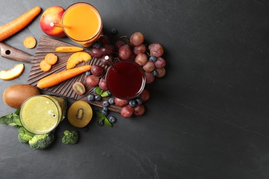 Photo of Delicious colorful juices in glasses and fresh ingredients on black table, flat lay. Space for text