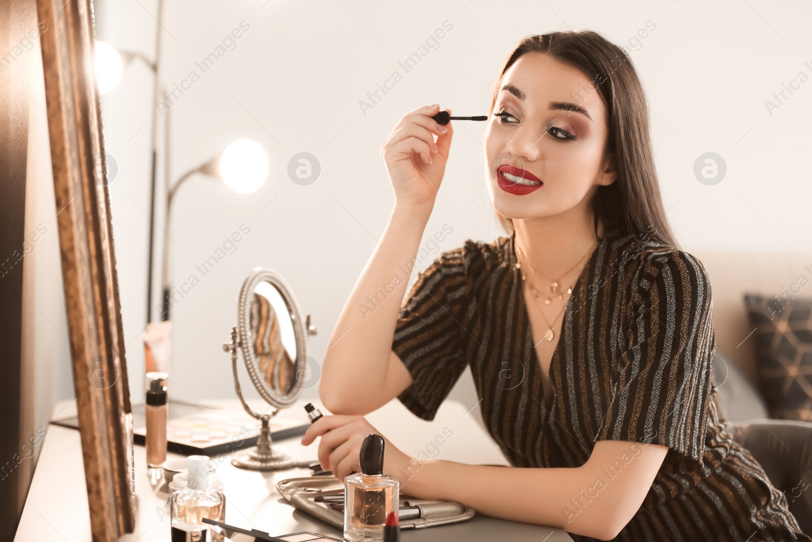 Photo of Portrait of beautiful woman applying makeup indoors