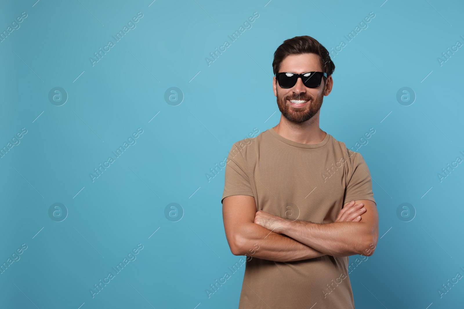 Photo of Portrait of smiling bearded man with stylish sunglasses on light blue background. Space for text