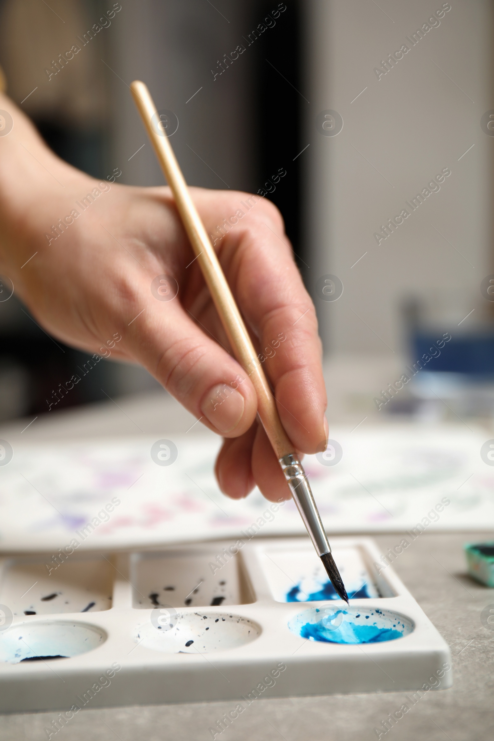 Photo of Woman painting with watercolor at grey stone table, closeup