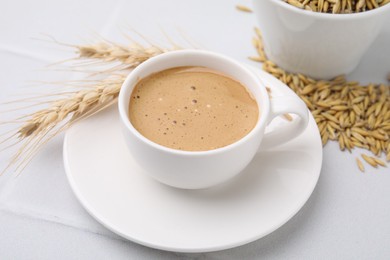Photo of Cup of barley coffee, grains and spikes on white table, closeup