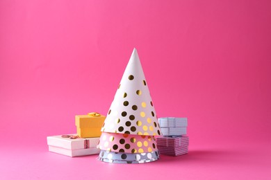 Party hats and gift boxes on pink background