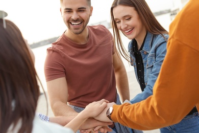 Photo of Group of happy people holding hands together, outdoors