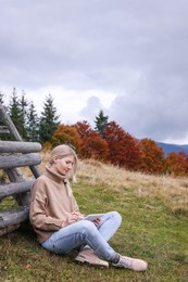 Young woman drawing on tablet in mountains, space for text