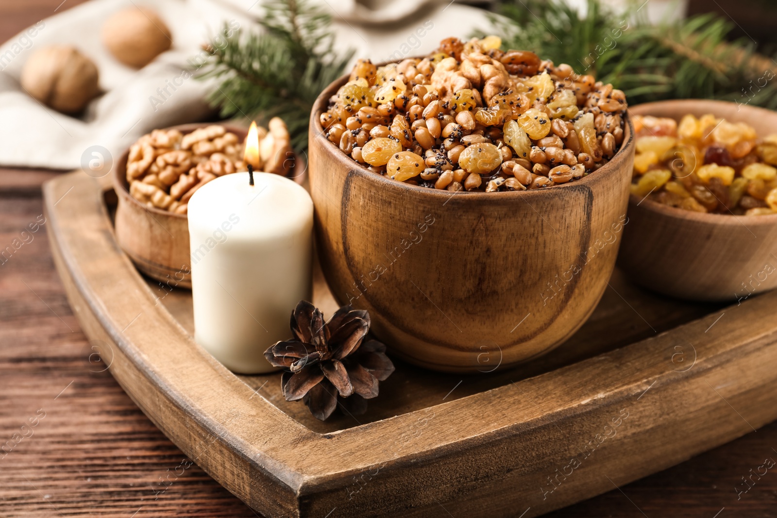 Photo of Traditional Christmas slavic dish kutia and burning candle on wooden table, closeup