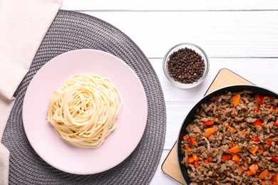 Photo of Delicious spaghetti, minced meat with carrot and pepper on white wooden table, flat lay