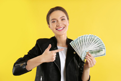 Young woman with money on yellow background