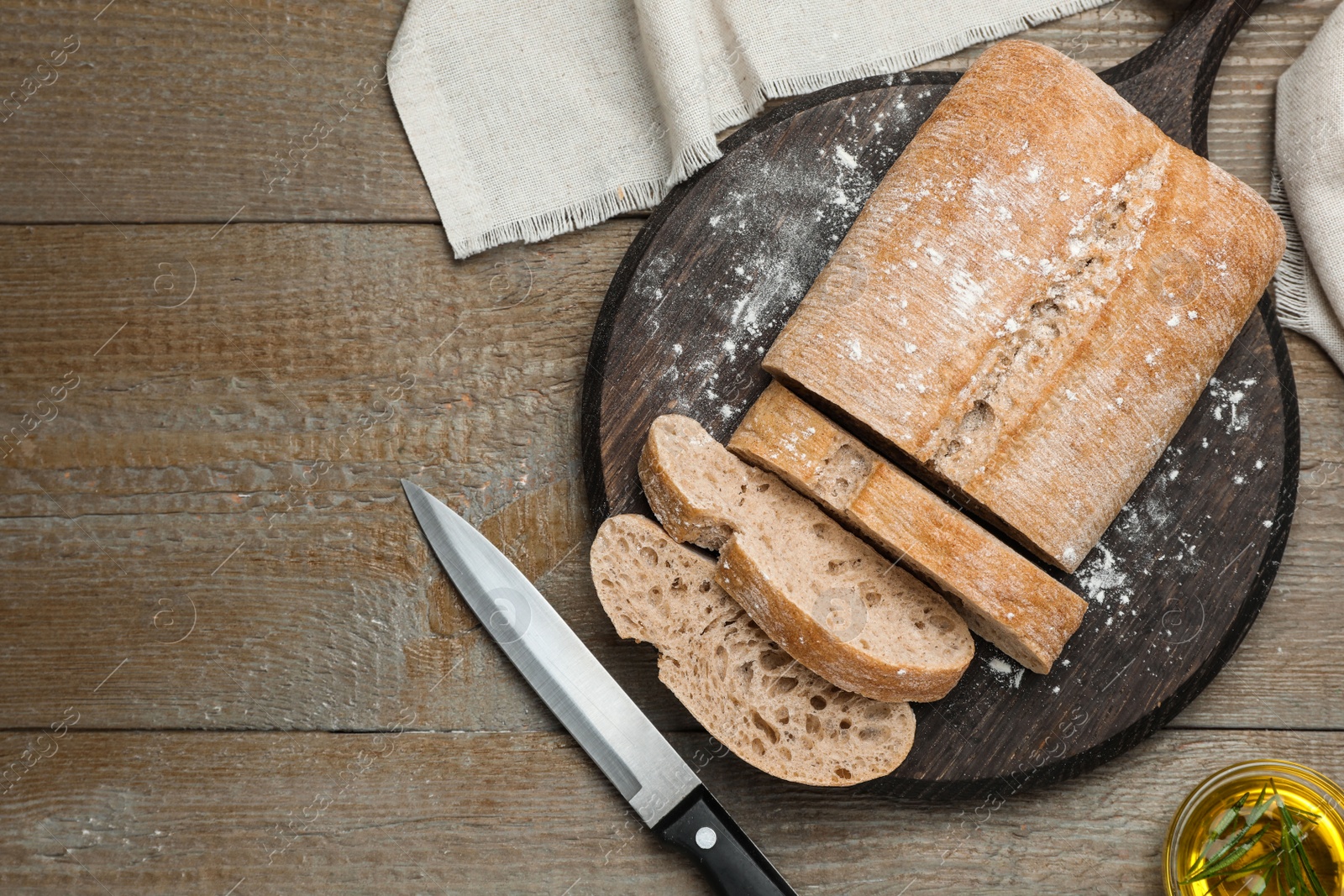 Photo of Cut delicious ciabatta on wooden table, flat lay. Space for text