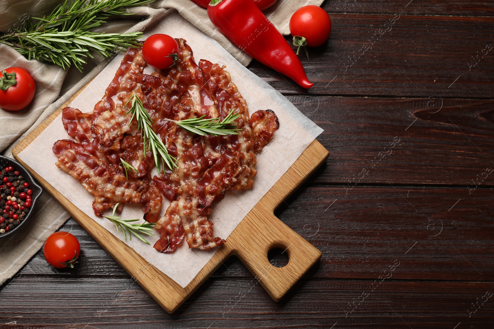 Photo of Slices of tasty fried bacon, tomatoes and different spices on wooden table, top view. Space for text