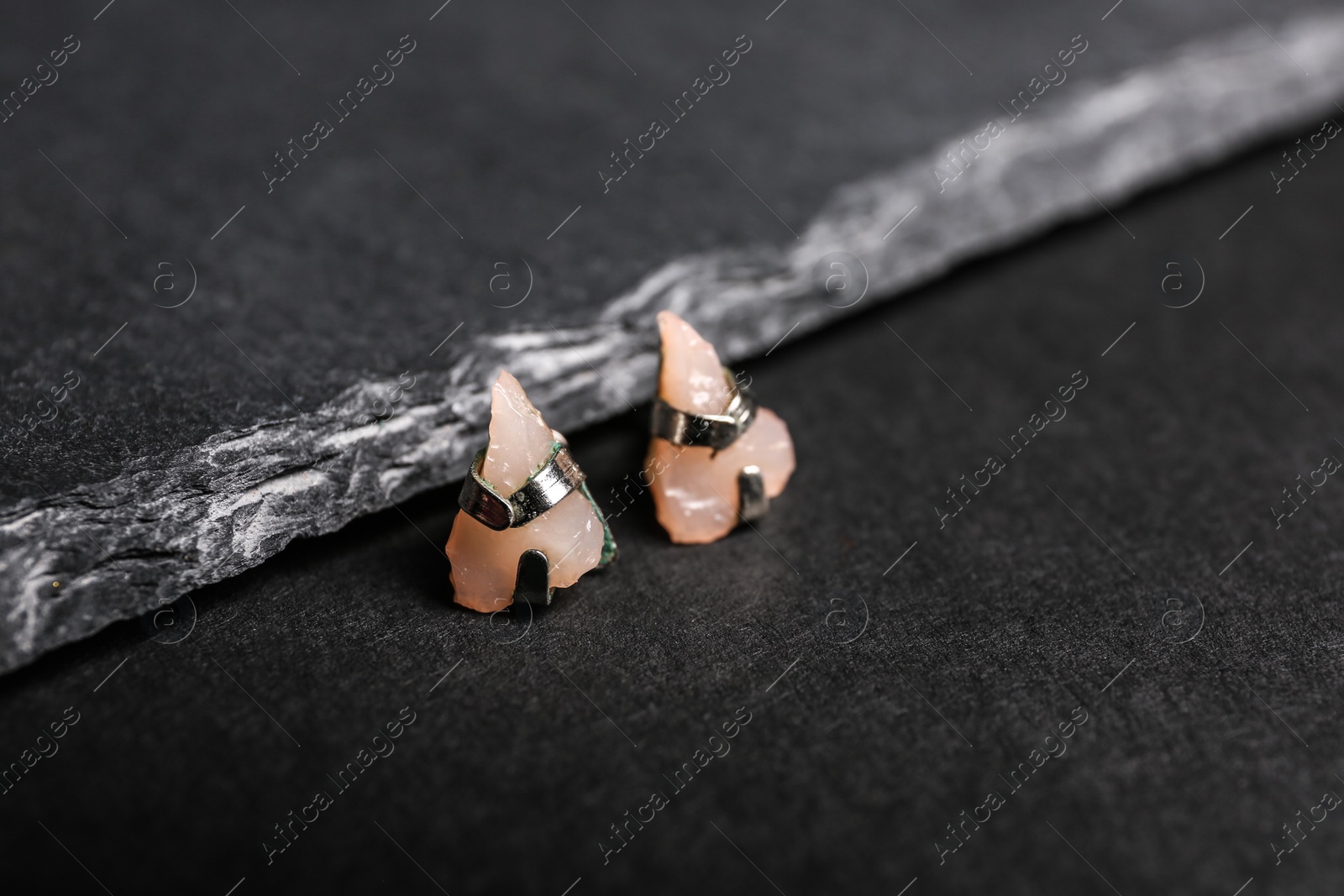 Photo of Stylish studs on black background, space for text. Luxury jewelry