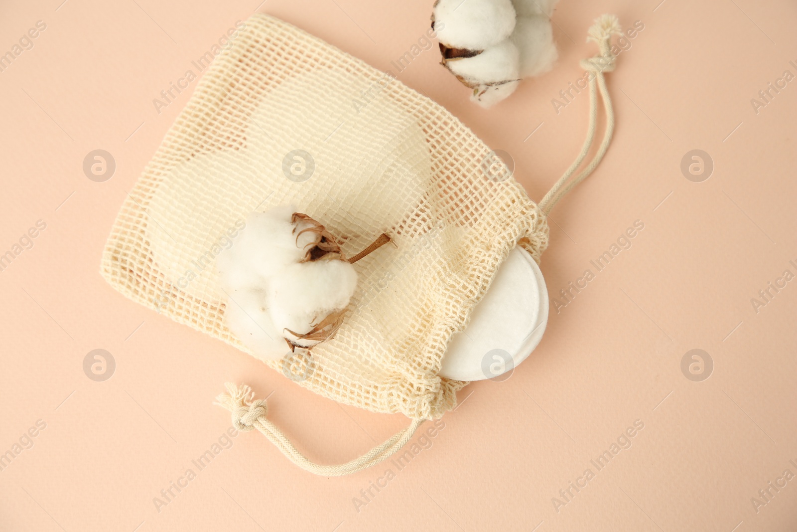 Photo of Bag with cotton pads and flowers on beige background, flat lay