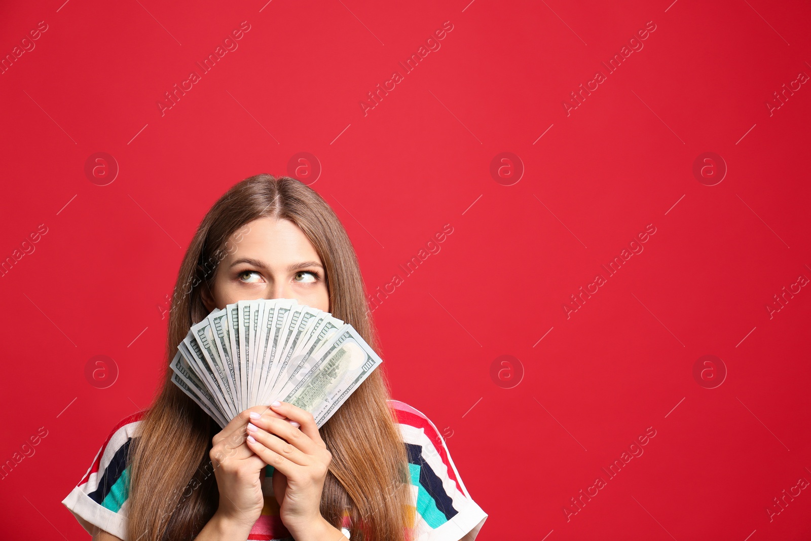 Photo of Portrait of thoughtful lottery winner with money on red background, space for text