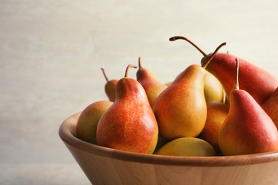 Photo of Bowl with ripe pears on light background, closeup