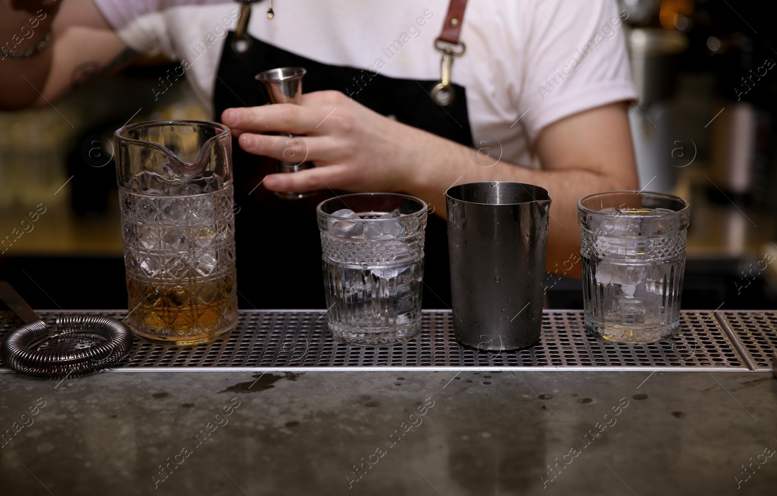 Photo of Bartender preparing tasty cocktail at counter in nightclub, closeup